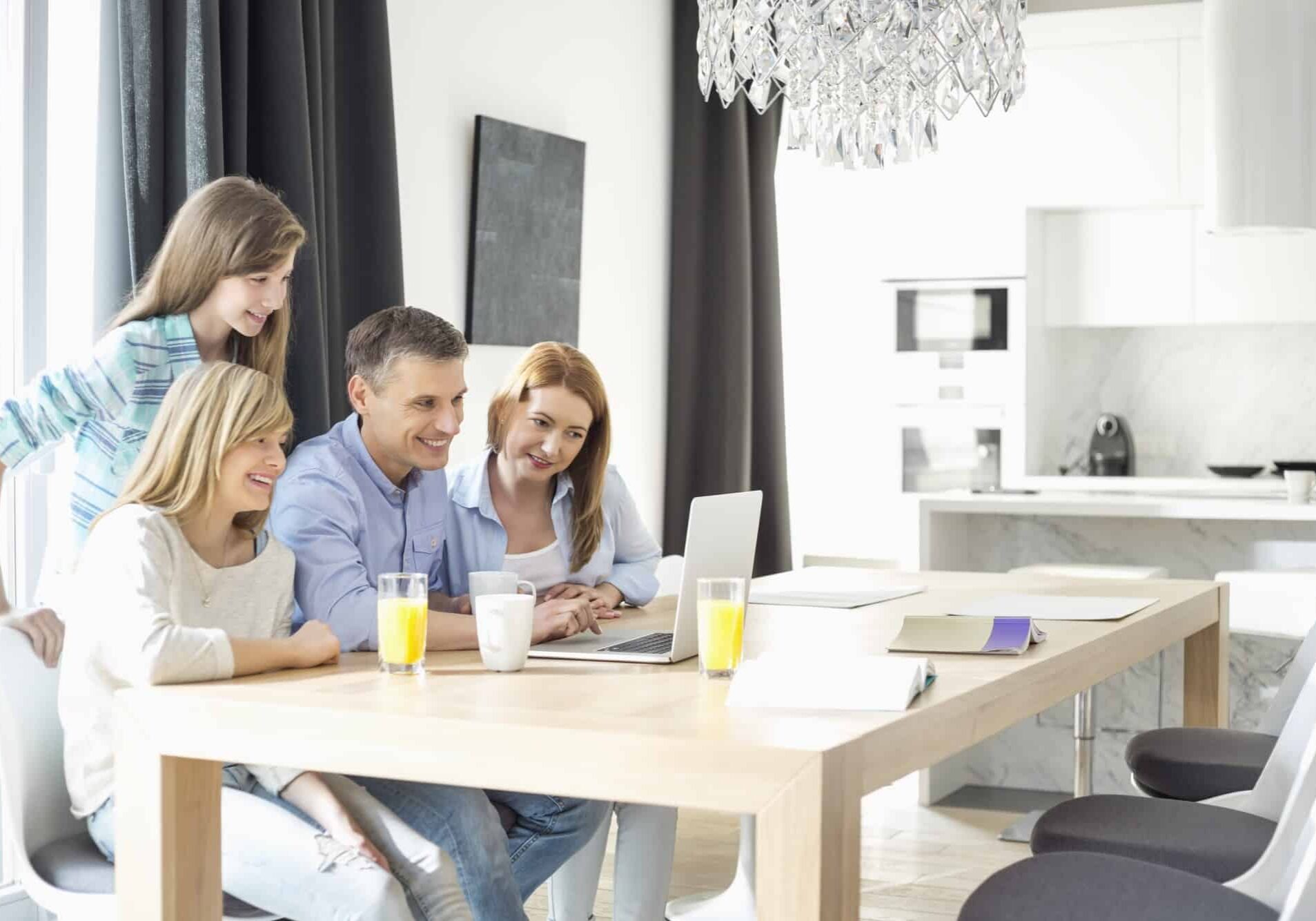 Happy family of four using laptop at home